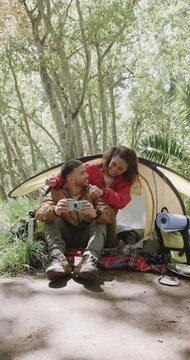 Vertical Video Of Biracial Couple Camping And Embracing In Forest, Slow Motion