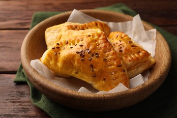 Fresh delicious puff pastry with cheese in bowl on wooden table, closeup