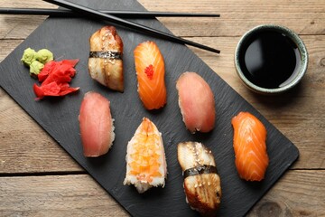 Serving board with delicious nigiri sushi and soy sauce on wooden table, flat lay