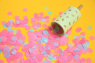 Party popper with bright confetti on orange background