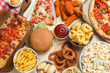 Pizza, chicken nuggets and other fast food on wooden table, flat lay