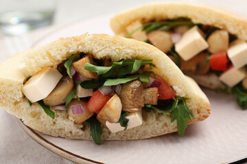 Delicious pita sandwiches with cheese, mushrooms tomatoes and arugula on table, closeup