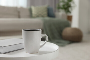 Ceramic mug and book on white table indoors. Mockup for design