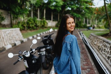 Naklejka premium Portrait of a woman brunette smile with teeth walking outside against a backdrop of palm trees in the tropics, summer vacations and outdoor recreation, the carefree lifestyle of a freelance student.