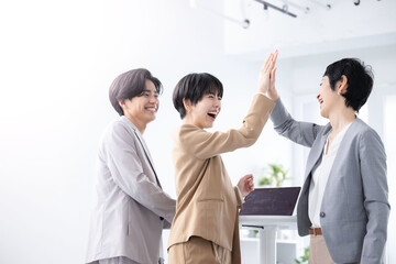 ハイタッチをして仕事の成功を喜ぶチーム　左にコピースぺースあり