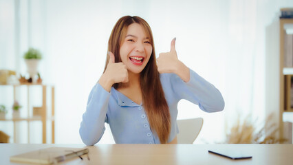 Happy teen asian girl blogger smiling face waving hand talking to webcam recording vlog, social...