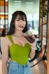 Portrait of beautiful sexy asian woman Wearing a green strapless dress and jean skirt in a cafe