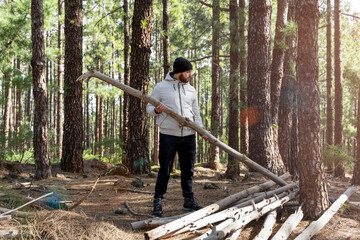 Chico colocando un tronco de madera junto a otros en el bosque 
