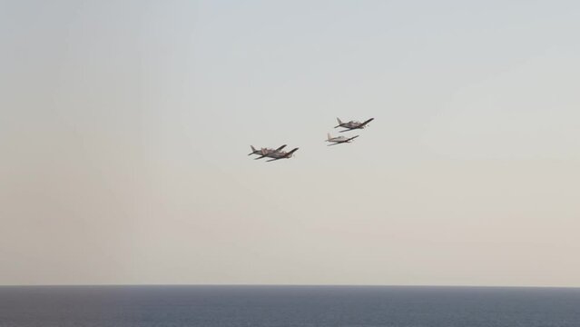 wide shot from far away of airplanes in air show with sea bottom.