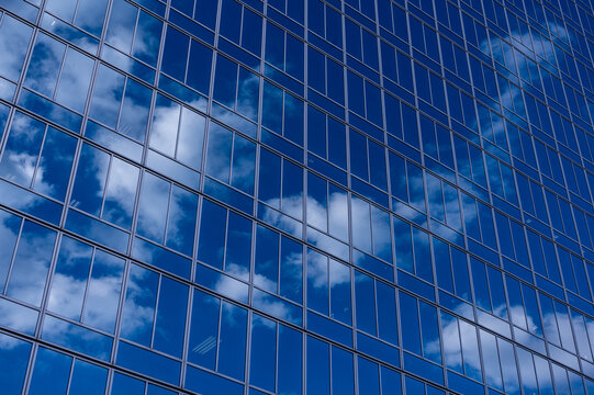 ガラス張りのビルに映る青空と白い雲