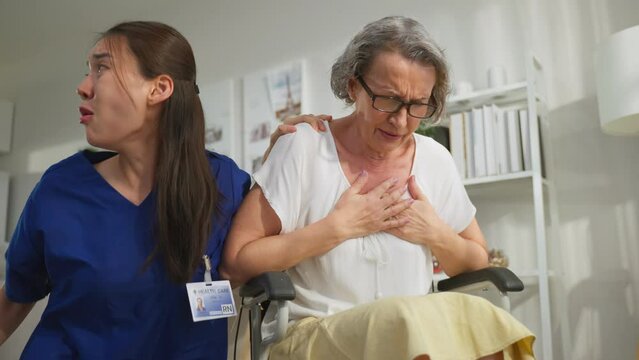 Asian caregiver saving senior woman having chest pain from heart attack. 