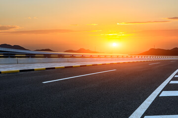Asphalt highway and mountain background at sunset