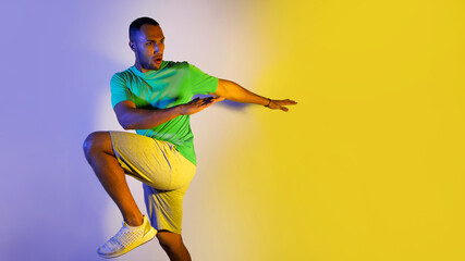 Fototapeta na wymiar Athletic Black Male Exercising Over Blue And Yellow Background