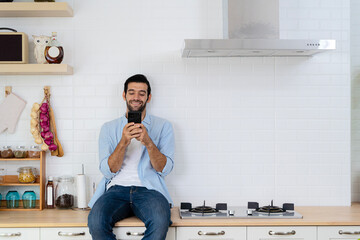 Handsome young man happy while sitting at home kitchen in good morning on leisurely vacation....