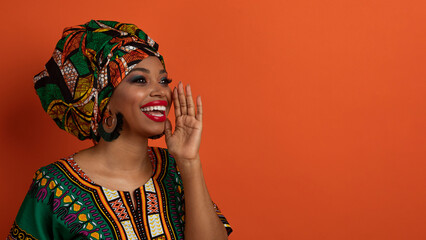 Attractive black woman in african costume screaming towards copy space - obrazy, fototapety, plakaty