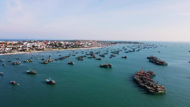 Large Mui Ne fishing fleet anchored along coastline, traditional boats; drone