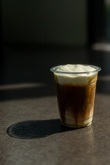 A plastic cup of coffee with a brown liquid in it.