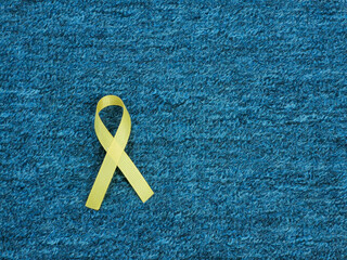 Yellow ribbon against blue carpet background.