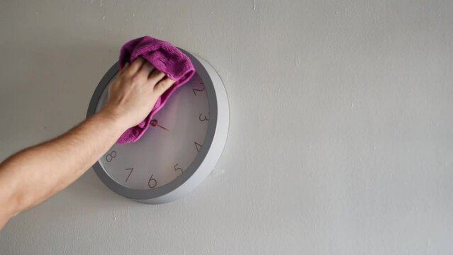 Hand cleaning a clock with background white and copyspace