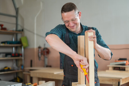 Caucasian man assembling a table with a screwdriver.