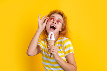 photo of girl eating cone icecream at summer. girl with cone icecream isolated on yellow.
