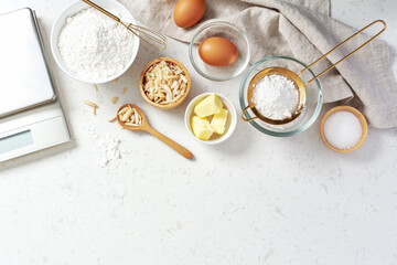 Baking and cooking ingredients, butter flour eggs and slivered almond with digital scale on marble background