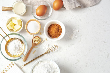 Baking pastry or cake ingredients, brown sugar, butter, flour, eggs and milk with utensil on marble...