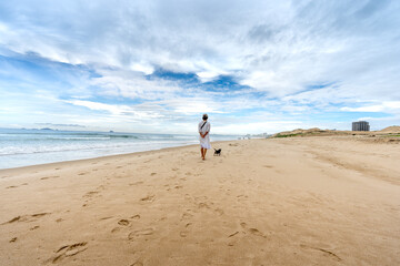 a woman walking with her dog walk on the beach at a tropical resort in Cam Ranh district, Khanh Hoa province, Vietnam
