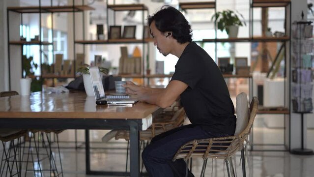 Asian freelancer online internet work home office. Boss guy use macbook computer indoor. Busy male man start up freelance job. User person sit inside cafe place. People study distant. Business laptop.