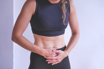 Athletic young woman holding her belly and suffering from pain in  stomach, menstrual spasm