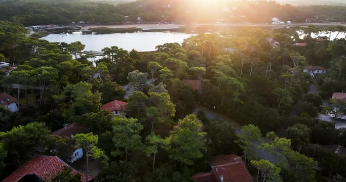 Drone flys over Hossegor Seignosse France Lakeside Town with many trees and homes with morning sunlight shining over