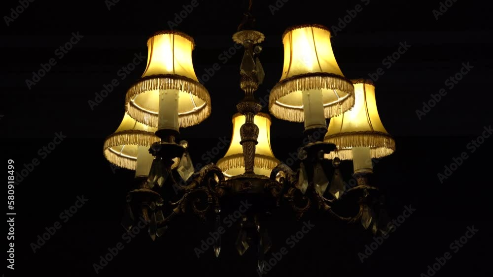Poster old british chandelier light in the dark hanging in a home with slow push in