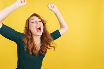 Happy redheaded woman celebrating while raising arms