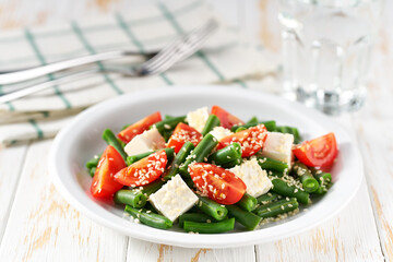 green bean salad with tomatoes, feta and sesame seeds close up.