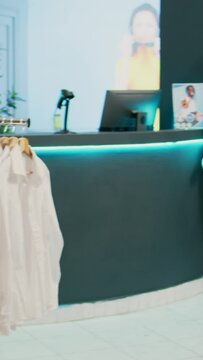 Vertical video: Empty clothing store filled with racks and hangers, elegant formal wear hanging in shopping mall retail boutique. Fashion shop with merchandise on sale, tailoring small business
