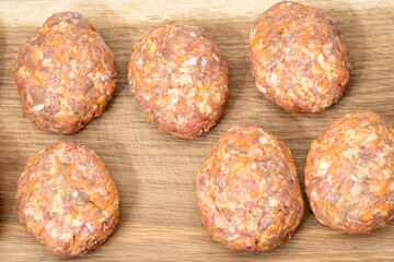 raw homemade meatballs on a massive board made of natural wood