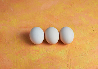 Three Easter white eggs on a yellow background
