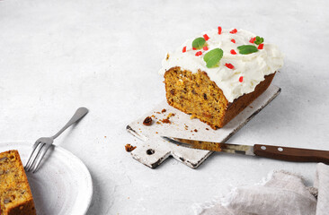 Cut of carrot cake with white icing on a board and plate, copy space