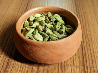 closeup of dried cardamom in the wooden plate, wooden background