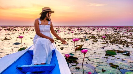 Asian women with a hat and dress in a boat at the Beautiful Red Lotus Sea Kumphawapi is full of...
