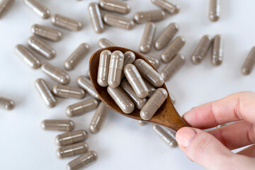 Pau D Arco brown herbal medicine capsules in a wooden spoon in a woman's hand. Close-up.