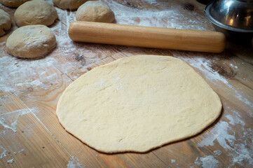 Closeup of rolling out pizza dough on the cooking table