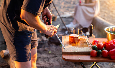 sharpening a knife in nature at a picnic for cooking. Camping. Fresh vegetables on the table, bushcraft