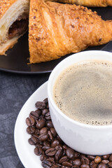 White cup of coffee and fresh croissant with chocolate for breakfast