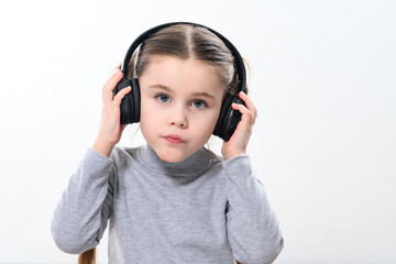 A child with headphones on a white background, a cheerful and beautiful girl with headphones.