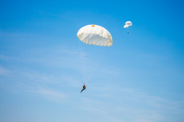 Skydiving. Flying parachutists against the background of the blue sky and mountains. Extreme sport and entertainment.