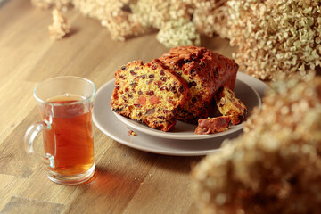  Fruit cake and tea on a wooden table with dried flowers.