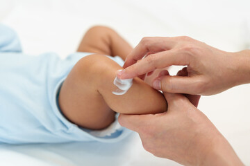 Fototapeta na wymiar mother applying moisturizing cream on leg of newborn baby