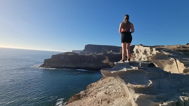 young woman observes the wonderful views located near the playa del medio Almud on the island of Gran canaria on a sunny day. Morgan municipality.