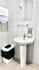 single sink in small public toilet with wall soap dispenser and paper towlels